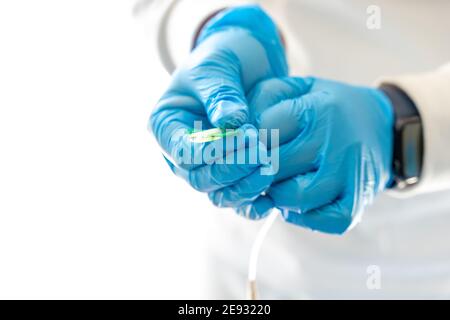 Crop anonimo medic in guanti di lattice e con ago per prelievo di campioni di sangue per il coronavirus Foto Stock