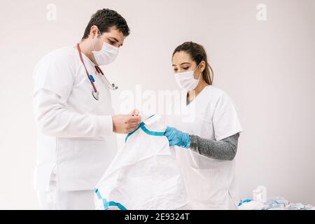 Medici di sesso maschile e femminile in maschere mediche in piedi con protettivo costume da infezione da coronavirus Foto Stock