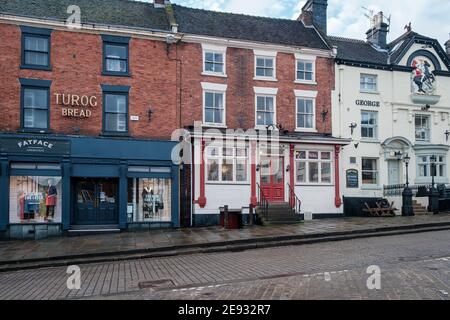 Un vecchio cartello su un ex panificio e sala da tè e edifici georgiani nel mercato, Ashbourne, Derbyshire Foto Stock