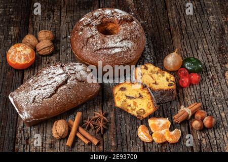 Composizione natalizia di frutta secca e stollen, con mandarino, su tavola testurizzata in legno, con spezie. A Natale. Foto Stock