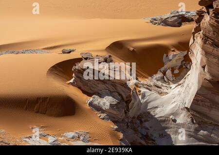 Una formazione di roccia bianca sminuzzante nelle sabbie arancioni curvy Del deserto del Sahara vicino a Ounianga Kébir Foto Stock