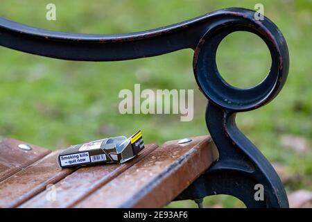Pacchetto di sigarette vuoto di Rothmans Blue lasciato su una panchina del parco in modo da infondere o portarlo a casa, Abington Park, Northapton, Inghilterra, Regno Unito. Foto Stock