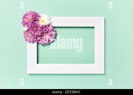 Composizione dei fiori. Cornice fotografica vuota e fiori su sfondo verde pastello. Giorno di San Valentino, giorno delle madri, giorno delle donne, concetto di primavera. Disposizione piatta, parte superiore Foto Stock