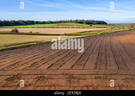 vista in alto del trattore rosso che arava un campo con preparato campo in primo piano Foto Stock