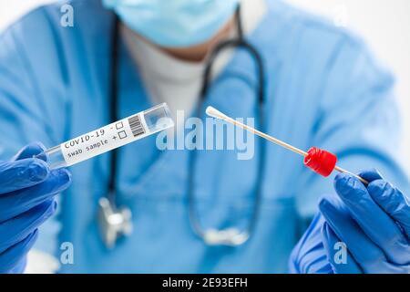 Kit per il prelievo dei campioni con tampone medico UK Worker Doctor, provetta per l'esecuzione di operazioni di swabbing nasale del paziente, indossare i guanti blu durante il test equam Foto Stock