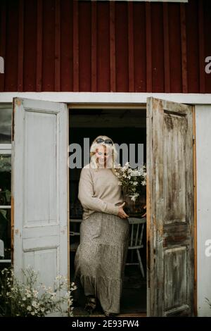 Donna sorridente che tiene bouquet di fiori in vaso Foto Stock