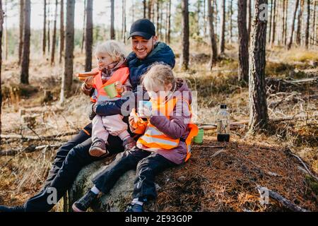 Padre e figlie che hanno pic-nic nella foresta Foto Stock