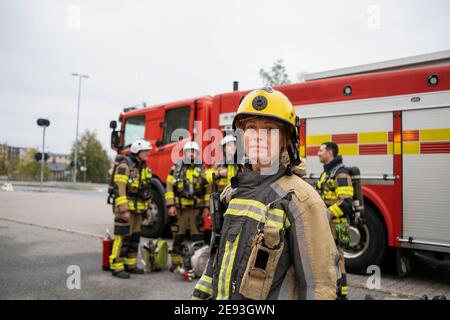 Pompiere femminile di fronte al motore antincendio Foto Stock