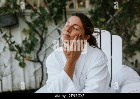 Donna sorridente l'applicazione di crema per il viso Foto Stock