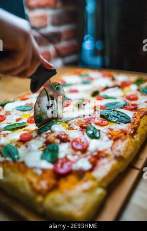 Affettare la pizza italiana con pomodori, formaggio e basilico Foto Stock