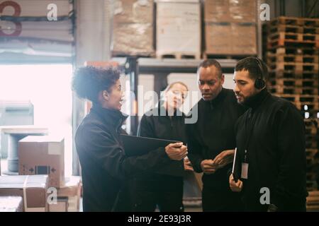 Donna imprenditore che discute con i colleghi durante la riunione in magazzino Foto Stock