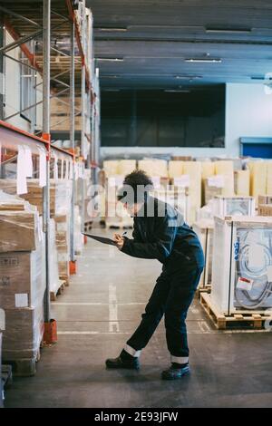 Operatrice manuale femminile che analizza i contenitori delle scatole nel magazzino di distribuzione Foto Stock