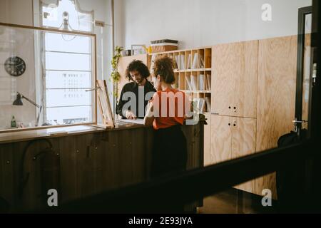 Imprenditore di sesso maschile che discute con la collega femminile su documento in ufficio Foto Stock