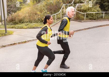 Donna non vedente che fa jogging con guida Foto Stock