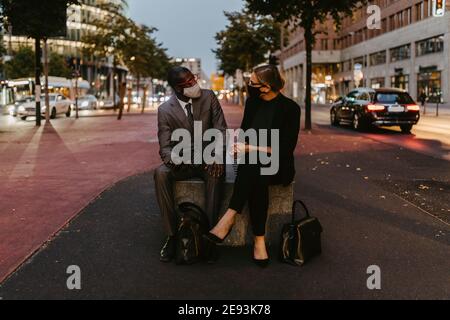 Uomo d'affari che discute con una collega femminile in città durante COVID-19 Foto Stock