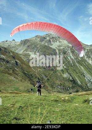 ALPES, FRANCIA - 26 giu 2018: Parapendio gonfiare la sua ala prima di decollarsi in una piccola valle circondata da montagne nelle Alpi francesi Foto Stock