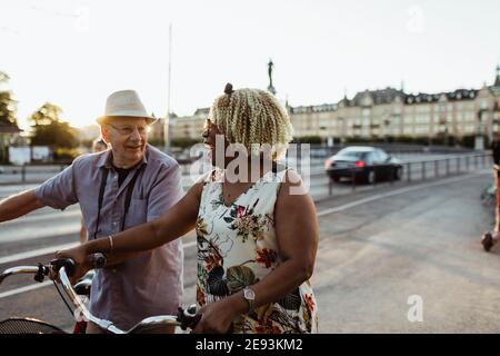 Coppia allegra con bicicletta su strada in città Foto Stock