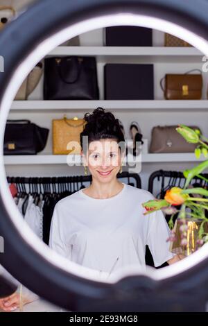 Influencer femminile con apparecchiature di illuminazione illuminate a casa Foto Stock