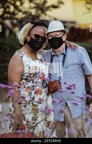 Coppia eterosessuale con braccio intorno in piedi nel parco durante la pandemia Foto Stock