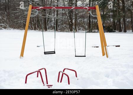 Parco giochi per bambini e bambini per giochi e attività vuote e coperto dalla neve in inverno durante la nevicata Foto Stock