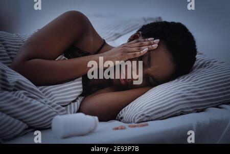 Stanco triste millennial afroamericano donna con gli occhi chiusi presse mani ai templi e soffre di mal di testa Foto Stock