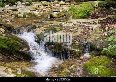 Una piccola cascata che scorre sui massi di un torrente (Marche, Italia, Europa) Foto Stock