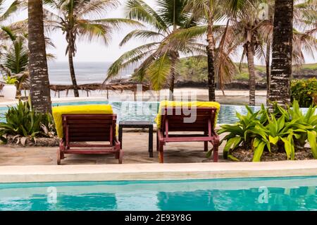 Due sedie a sdraio lungo la piscina che si affaccia sull'Oceano Indiano Watamu Beach in Kenya Foto Stock