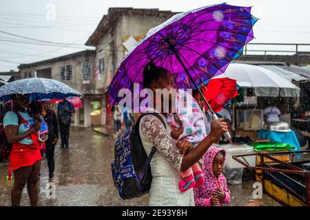 Una giovane donna afro-colombiana, che porta il suo bambino, cammina in un mercato di strada lungo il fiume Atrato a Quibdó, Chocó, la regione pacifica della Colombia. Foto Stock