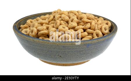 Vista laterale di cereali interi secchi rotondi di avena in una vecchia ciotola di gres blu isolata su sfondo bianco. Foto Stock