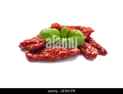 Focalizzazione selettiva sui deliziosi pomodori spagnoli essiccati al sole e ricoperti di olio con foglia di basilico isolata su sfondo bianco Foto Stock