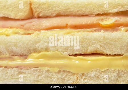 sandwich farcito prosciutto e formaggio confezionamento in plastica trasparente su sfondo bianco Foto Stock