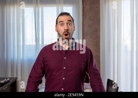 Un giovane bell'uomo porticato che indossa una camicia che guarda spaventato e sorpreso con un'espressione sconvolgente e sorprendente. Concetto di sorpresa Foto Stock