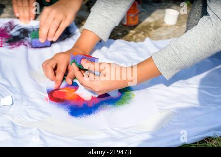 Crea la tua t-shirt workshop all'esterno. Applicare la mano di vernice sulla camicia Foto Stock