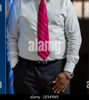 Colpo verticale di un maschio che indossa abiti formali con un cravatta rosa Foto Stock