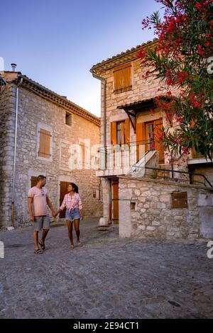 Una coppia visita Ruoms, il borgo medievale di Ruoms con le sue vecchie case in mattoni e i piccoli vicoli sul fiume Ardeche in Francia. Europa Foto Stock