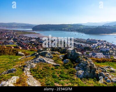 View looking down over Deganwy and the mouth of the River Conwy in Conwy North Wales from the ruins of Deganwy Castle with rocks in foreground. Foto Stock