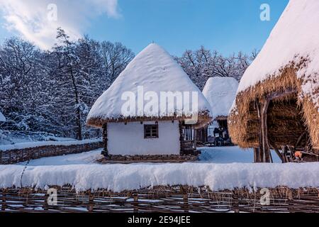 Tradizionale villaggio rumeno in Transilvania con vecchia casa tetto di paglia coperto di neve in una giornata fredda Foto Stock