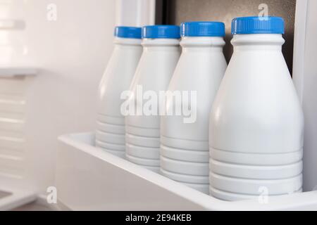 Gruppo di contenitori per latte in plastica conservati e allineati nello sportello del frigorifero. Il calcio è buono per la vostra salute Foto Stock