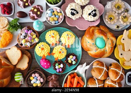 Tavola pasquale con un assortimento di pane, dessert e prelibatezze. Vista dall'alto su uno sfondo di legno. Concetto di cibo per le vacanze primaverili. Foto Stock