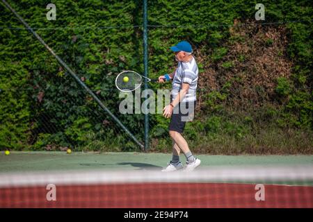 Uomo anziano che gioca a tennis all'aperto sul campo da tennis, concetto sportivo Foto Stock