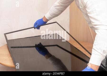Il tecnico del centro di assistenza rimuove la cornice dal TV LCD. Riparazione del monitor, messa a fuoco selettiva. Foto Stock