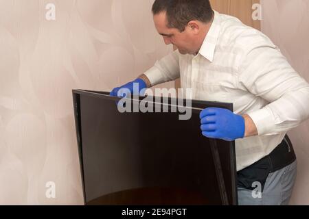 Il tecnico rimuove il telaio del monitor presso il centro di assistenza. Riparazione TV LCD. Messa a fuoco selettiva. Foto Stock