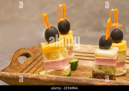 Deliziose tartine sugli spiedini con prosciutto, formaggio, pane e olive. Tavolo a buffet, primo piano, messa a fuoco selettiva. Foto Stock