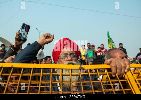 Gli agricoltori si levano in piedi dietro le barriere installate e gridano slogan durante i manifestimentre la protesta degli agricoltori contro i tre atti agricoli continua sul confine di Ghazipur, la polizia di Delhi ha sigillato il confine con barriere, muro di cemento e filo spinato per impedire agli agricoltori di accedervi per le loro proteste. Foto Stock