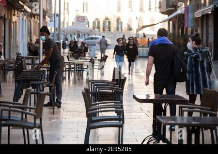 Malaga, Spagna. 2 Feb 2021. Un lavoratore accatastato sedie al di fuori della terrazza vuota del ristorante la plaza Malaga durante la chiusura del settore dell'ospitalità e attività non essenziali come parte di una chiusura parziale. Per due settimane, oltre al limite di mobilità tra città, molti comuni e distretti della Costa del Sol (compresa la capitale di Malaga) dovrà chiudere bar, ristoranti e negozi come misure per frenare la diffusione della pandemia di coronavirus. In Andalusia, Malaga è la città con più infezioni da coronavirus quotidiano e un alto tasso di ricoveri. (Imag. Credito Foto Stock