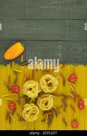 Gli spaghetti secchi e i tagliatelle fatti in casa sono disposti sul tavolo. Sfondo con posizione per il testo. Pasta e spezie vengono spruzzate sul tavolo Foto Stock