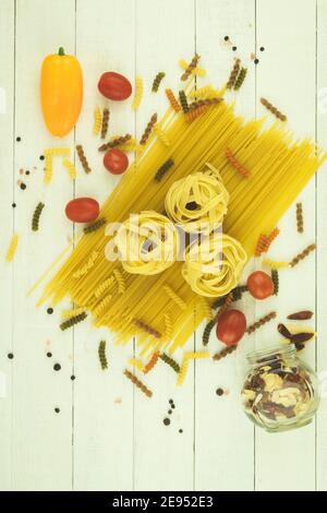 Gli spaghetti secchi e i tagliatelle fatti in casa sono disposti sul tavolo. Sfondo con posizione per il testo. Pasta e spezie vengono spruzzate sul tavolo Foto Stock