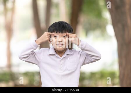 Bambino asiatico che si diverse a fare un viso divertente. Un ragazzo con una faccia cheeky. Foto Stock