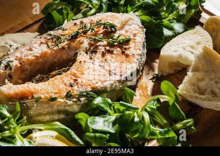 Bistecca di salmone al forno con salsa al timo e alla crema, insalata di mais, pane e formaggio blu su tavola rustica di legno direttamente sopra. Pasto preferito, cibo sano Foto Stock
