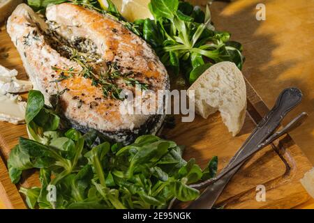 Bistecca di salmone al forno con salsa al timo e alla crema, insalata di mais, pane e formaggio blu su tavola rustica di legno direttamente sopra. Pasto preferito, cibo sano Foto Stock